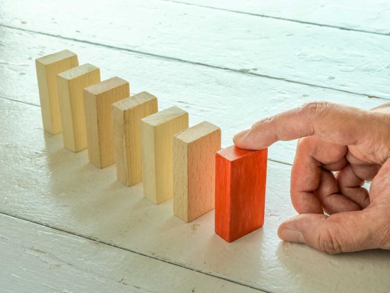 A line of blocks with one colored and a finger.