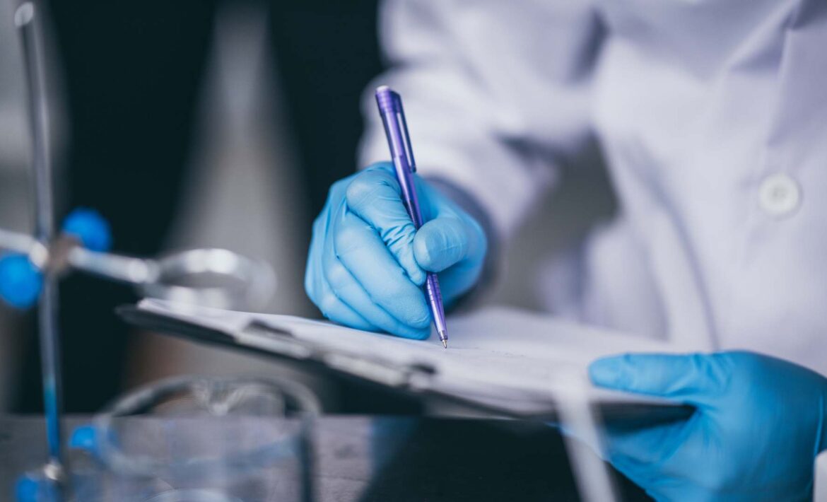 Lab technicians writing on a report with blue gloves.