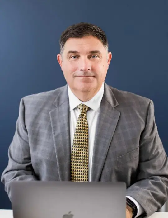 Marc LeBeau Portrait Smiling to Camera with hands on laptop.