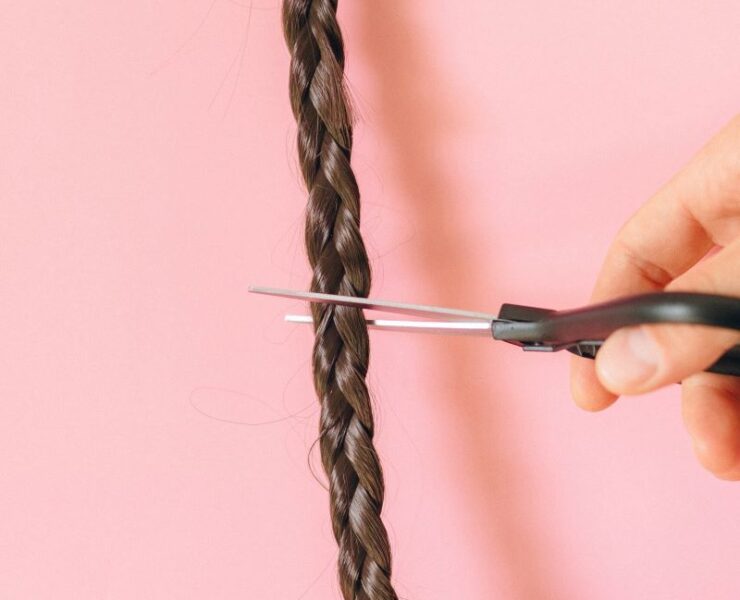 Braided long hair being cut using scissors.