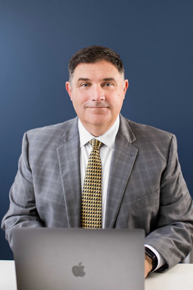 Marc LeBeau Portrait Smiling to Camera with hands on laptop.