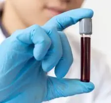 Lab technician holding a vial of blood.